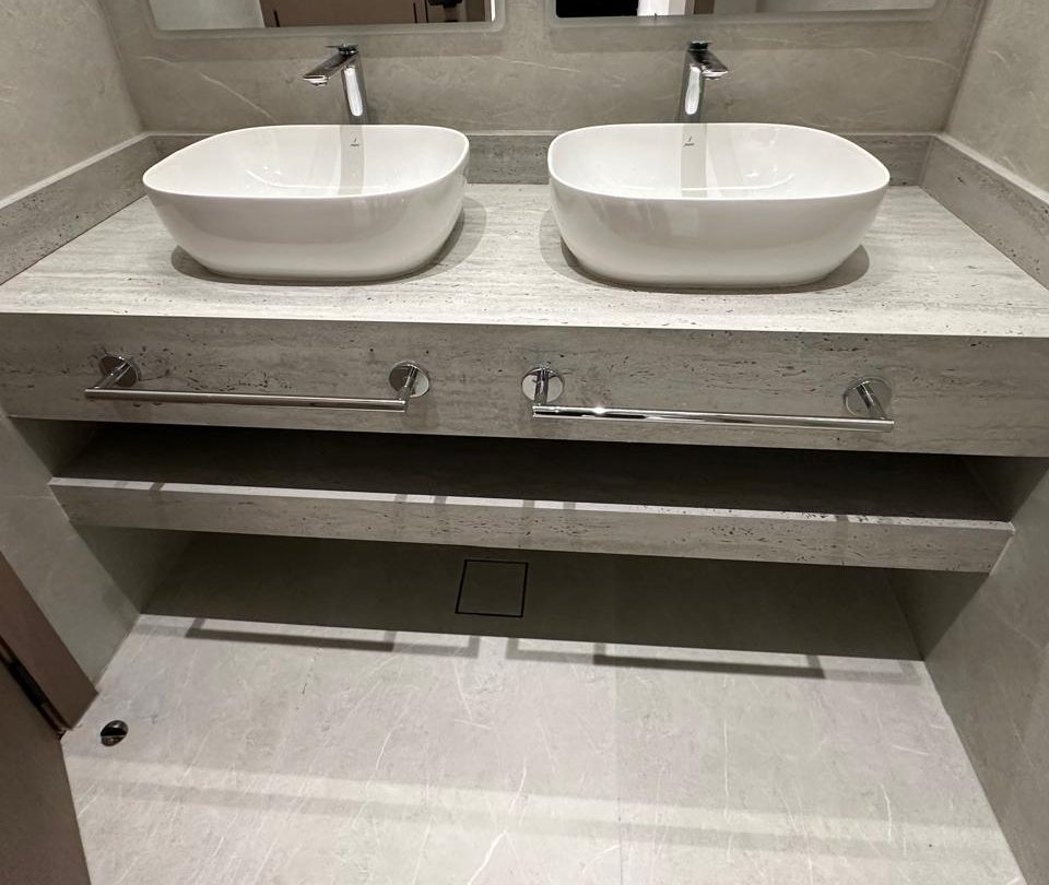 Finished bathroom: double vessel basins on a stone-clad floating vanity with chrome towel rails
